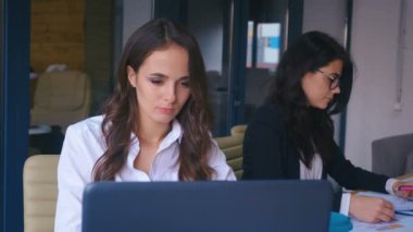 Kadın çalışanlar ofiste çalışıyor. Modern Ofiste Dizüstü bilgisayarla çalışan Gözlüklü Çekici Genç İş Kadını