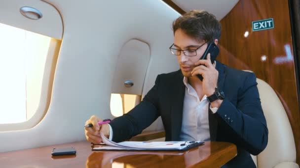 Occupato uomo d'affari lavora con i documenti e parlare sul telefono cellulare durante il volo in un aereo jet personale. Aereo Business Class . — Video Stock