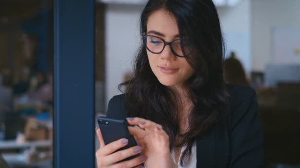 Portrét krásné mladé ženy pomocí chytrého telefonu v kanceláři. Obchodní dáma ve formálním oblečení šaty psaní zprávy na svém mobilním telefonu. — Stock video