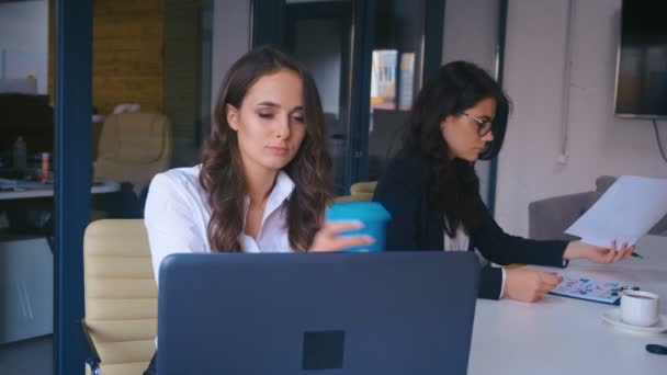 Aantrekkelijke jonge zakenvrouw Werken op een laptop in Modern Office. Afhaalkoffie drinken. — Stockvideo