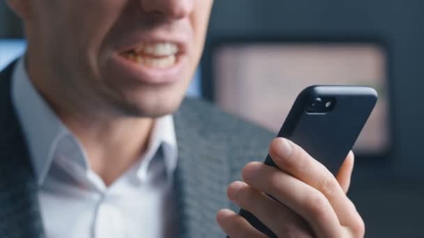 Agressieve zakenman aan het praten op een videogesprek op een mobiele telefoon. De man schreeuwt furieus en toont agressie aan de gesprekspartner. Kantoorachtergrond. Stress op het werk. — Stockvideo