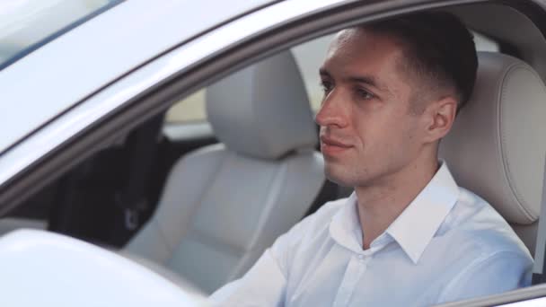 흰색 셔츠를 입은 남성 사업가 가 운전석에 앉아 웃으며 차에 앉아 있는 모습. — 비디오