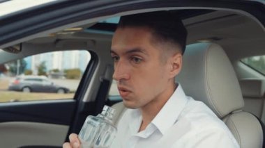Sürücünün portresi arabada otururken alkollü bir içki içiyor..