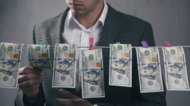Erkek suçlu para aklar. Bir adam dolarları iple kurutur. Ekonomik suç kavramı.