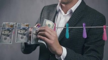 Erkek suçlu para aklar. Bir adam dolarları iple kurutur. Ekonomik suç kavramı.