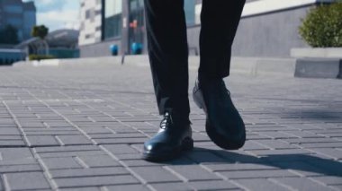 İşe gidip gelen bir iş adamının önü. Deri ayakkabılı, takım elbiseli, kendine güveni tam bir adam iş yerinin caddesinde yürüyor.