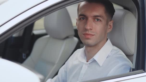 Retrato de homem de negócios com uma camisa branca sentado em um carro em um assento de motorista e sorrindo . — Vídeo de Stock