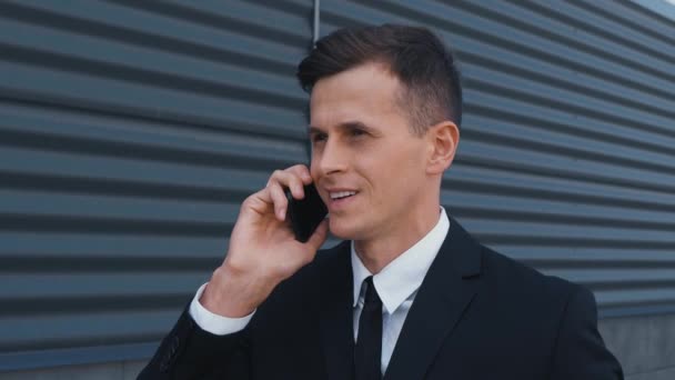 Красивий бізнесмен ходить по вулиці біля офісного центру і розмовляє на мобільному телефоні. Бізнес, люди. Носіння класичного костюма — стокове відео