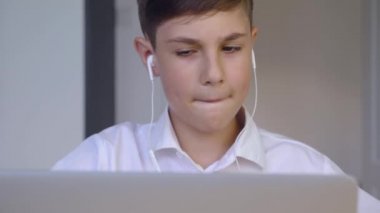 Kulaklıklı öğrenci evde online eğitim için dizüstü bilgisayar kullanıyor. Çocuk online okul ödevi yapmaktan hoşlanıyor. Genç iş adamı laptopta çalışıyor ve kahve içiyor.