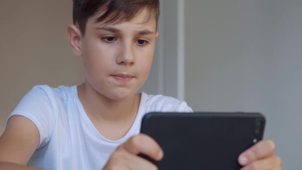 Primer plano retrato de niño jugando juego móvil en el teléfono inteligente en casa. Preescolar jugando al teléfono móvil. Niño usando el teléfono para jugar. Niño jugando videojuego . — Vídeos de Stock