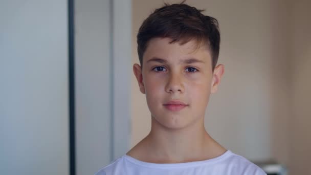 Retrato de niño guapo de 12 años en camiseta blanca mirando a la cámara en casa — Vídeos de Stock