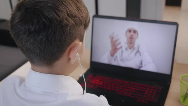 Vista posteriore del ragazzo consultazione online con un medico pediatrico. — Video Stock