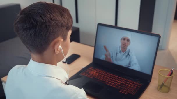 Vue arrière d'un garçon consultation en ligne avec un médecin pédiatre. — Video