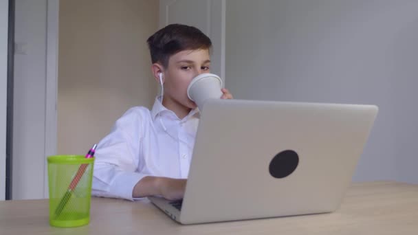 Yakışıklı genç iş adamı evde dizüstü bilgisayarda çalışıyor ve kahve içiyor. Çevrimiçi öğrenme, mesafe dersi, evde eğitim. Çocuk dizüstü bilgisayar kullanıyor. — Stok video