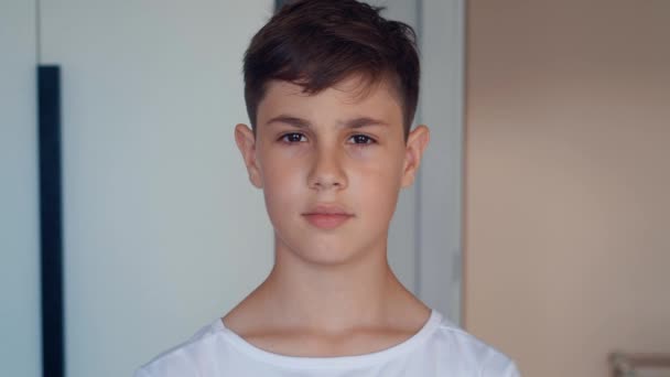 Portrait of handsome boy of 12 ages in white shirt looking at camera at home — Stock Video