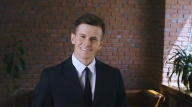 Modern bir ofiste gülümseyen bir iş adamının portresi. Takım elbiseli ve kameraya bakan yakışıklı iş adamı.