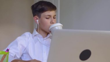 Kulaklıklı öğrenci evde online eğitim için dizüstü bilgisayar kullanıyor. Çocuk online okul ödevi yapmaktan hoşlanıyor. Genç iş adamı laptopta çalışıyor ve kahve içiyor.
