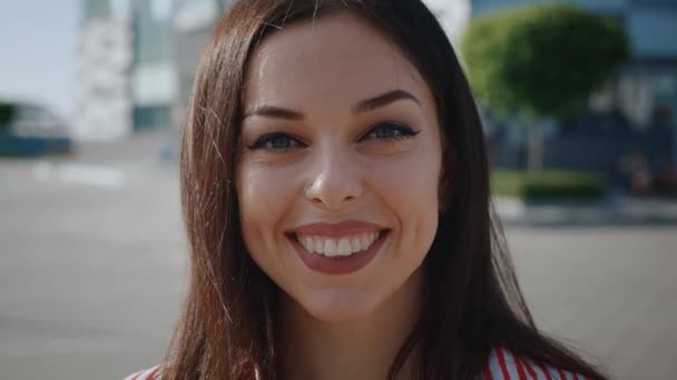 Retrato de uma mulher despreocupada feliz sorrindo em frente ao fundo da cidade, Close-up rosto de jovem sorrindo com os dentes ao ar livre . — Vídeo de Stock