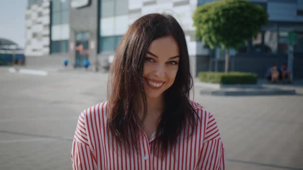 Portrait d'une femme heureuse et insouciante souriante devant le fond de la ville, Gros plan sur le visage d'une jeune femme souriante avec les dents à l'extérieur. — Video