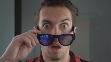 Şok olmuş ve şaşırmış genç bir adam. Sürpriz yapan hippi adam güneş gözlüğü atıyor ve kameraya şaşkınlıkla bakıyor..