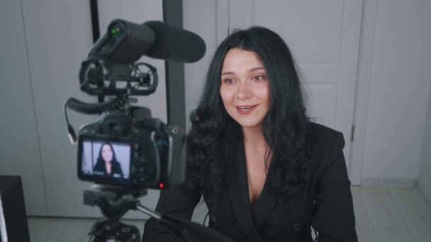 Молода жінка-блогер записує відео для входу в Інтернет за допомогою професійної камери. Жіночий відео блогер розмовляє з камерою вдома — стокове відео
