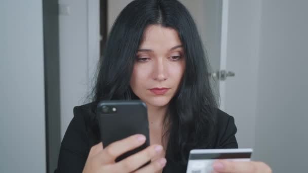 Mujer joven de compras en el teléfono móvil con tarjeta de crédito. Joven cliente sonriente sosteniendo tarjeta de crédito y teléfono inteligente haciendo compra en la tienda en línea. Servicio de aplicaciones de banca electrónica . — Vídeos de Stock