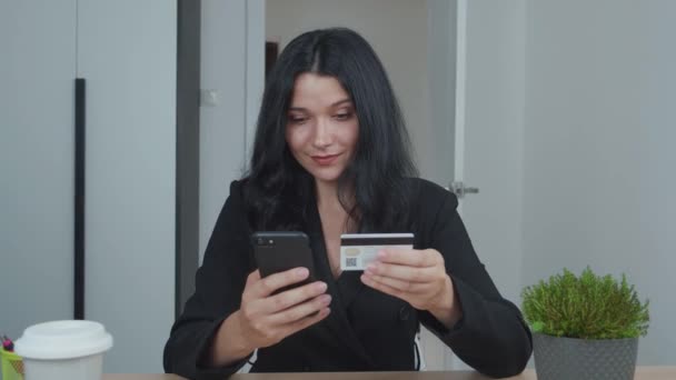 Egy fiatal nő mobilon vásárol hitelkártyával. Mosolygó fiatal nő ügyfél kezében hitelkártya és okostelefon, hogy vásárlás online áruház. Elektronikus banki alkalmazásszolgáltatás. — Stock videók