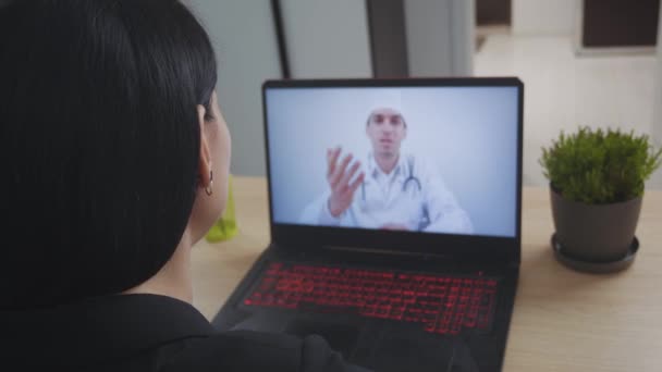 Médico masculino videoconferencia mujer joven consultoría a distancia paciente durante la telemedicina videollamada en conferencia webcam virtual chat aplicación. Vista de pantalla portátil sobre hombro . — Vídeos de Stock