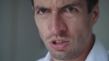 Suratı asık bir adam yüksek sesle bağırıyor. Bağıran kızgın adamın yakın plan ağzı. Şiddet tehdidi.