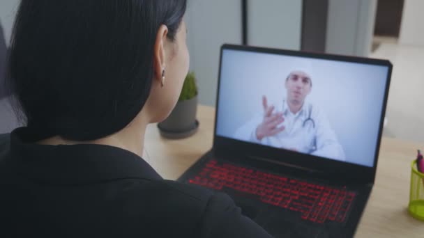 Man arts videoconferencing jonge vrouw externe patiënt consulting tijdens telegeneeskunde video call in conferentie virtuele webcam chat app. Over schouder laptop scherm te bekijken. — Stockvideo