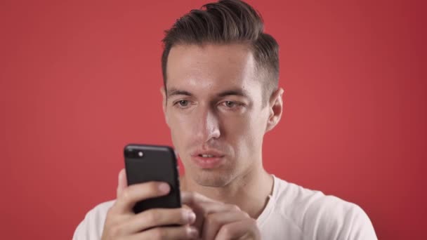 Podekscytowany człowiek zwycięzca trzymać smartfona czuć zdumiony overjoyed z telefonu komórkowego oferty gry online gra aplikacja wygrać na czerwonym tle, szczęśliwy ekstatyczny mężczyzna używać spojrzeć na telefon komórkowy świętować przeczytać dobrą wiadomość — Wideo stockowe