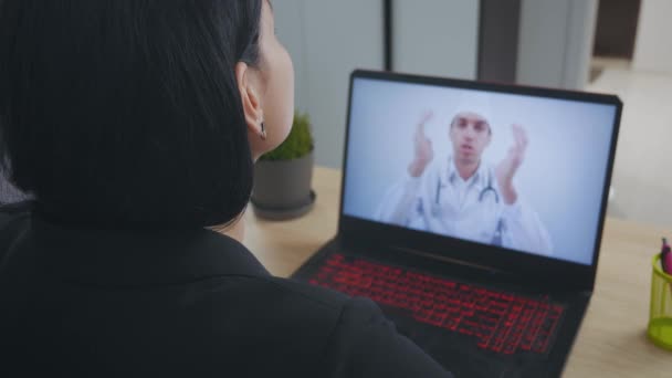 Médico masculino videoconferencia mujer joven consultoría a distancia paciente durante la telemedicina videollamada en conferencia webcam virtual chat aplicación. Vista de pantalla portátil sobre hombro . — Vídeos de Stock