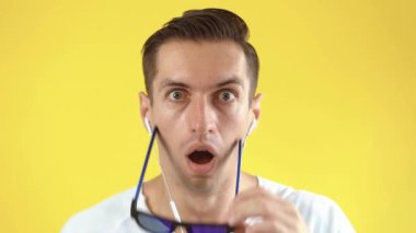 Şok olmuş ve şaşırmış genç adam sarı arka planda. Sürpriz yapan hippi adam güneş gözlüğü atıyor ve kameraya şaşkınlıkla bakıyor..