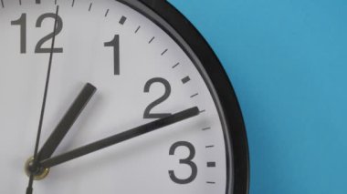 Yakın plan beyaz ofis saati mavi bir duvarda asılı..