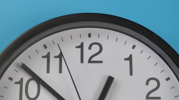 Close-up pojedynczy biały zegar biurowy wiszący na niebieskim kolorze ściany. — Wideo stockowe
