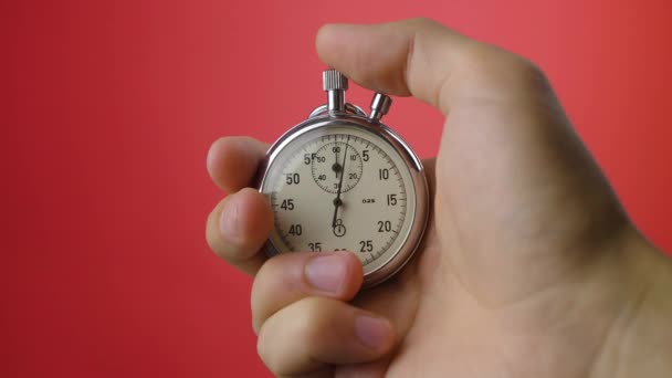 Mannelijke hand met analoge stopwatch op rode achtergrond. Tijd start met oude chronometer man drukt op start knop in de sport concept. Tijdbeheerconcept. — Stockvideo