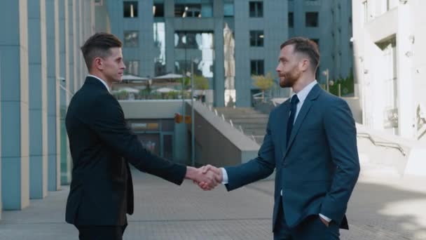 Dua pria bisnis berjabat tangan ketika bertemu, setuju untuk kesepakatan atau menyapa. Potret jabat tangan dari dua pengusaha sukses membuat kesepakatan. Gedung perkantoran di latar belakang. Distrik bisnis. — Stok Video