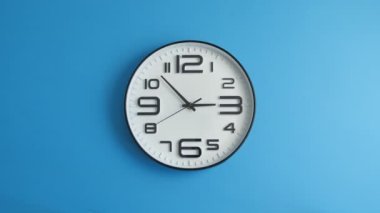 Mavi duvarda asılı beyaz ofis saati.