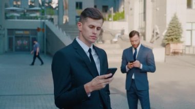 Yakışıklı İşadamı İş Mahallesindeki Akıllı Telefonunda Uygulama Kullanıyor. Haberleri kontrol ediyorum, Mails. Kendinden emin ve başarılı görünüyorsun. Takım Elbiseli.