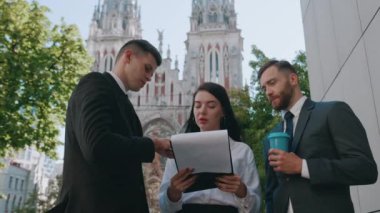 Bir grup genç iş adamı iş merkezinin ofis binasının yakınındaki sokakta girişim ve satış büyümesini tartışıyor..