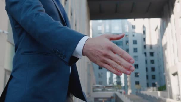 ビジネススーツのトップマネージャーの手を閉じて、ビジネスセンターの背景で互いに握手し、契約に同意します。誰も知らない. — ストック動画