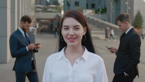 Портрет красивой и уверенной молодой женщины в формальном костюме, стоящей на улице и позирующей перед камерой с счастливой улыбкой в деловом районе города — стоковое видео