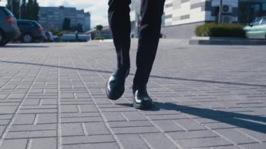 İşe gidip gelen bir iş adamının önü. Deri ayakkabılı, takım elbiseli, kendine güveni tam bir adam iş yerinin caddesinde yürüyor.