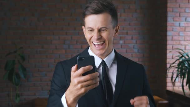 商人使用智能手机的肖像。《胜利的反应：兴奋男人的成功》在他的智能手机上得到了好消息. — 图库视频影像