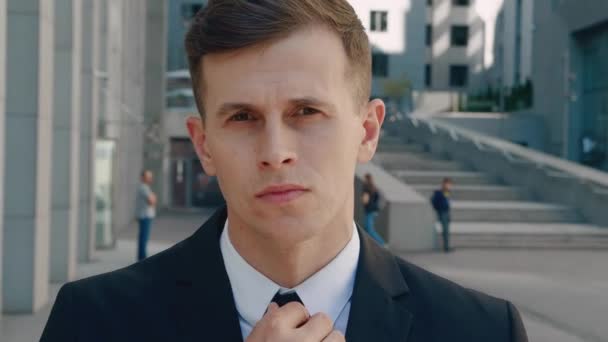 Close up attractive man in business suit in looking into camera in the city on downtown district. Portrait of confident male businessman standing outdoor near office building. — Stock Video