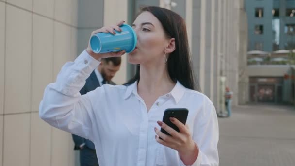Portrait de belle jeune femme d'affaires utilisant SmartPhone sur pause café en plein air sur les rues du quartier des affaires. Groupe de gens d'affaires occupés sur le fond. — Video