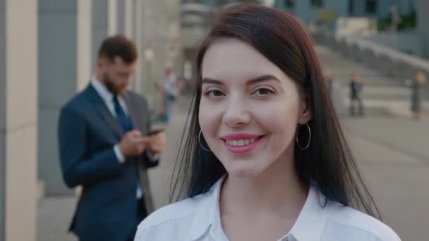 Retrato de mujer joven hermosa y confiada en traje formal de pie al aire libre y posando para la cámara con sonrisa feliz en el distrito de negocios del centro — Vídeo de stock