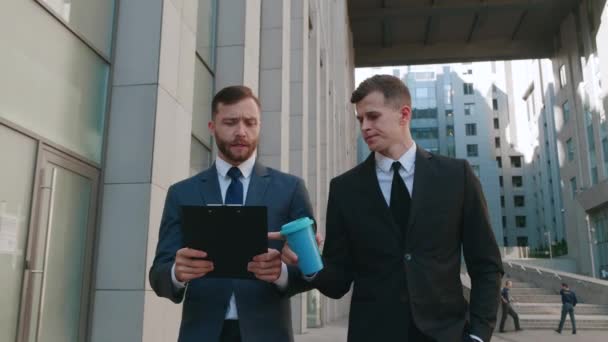 Deux gestionnaires de bureau se rendent au travail et interagissent entre eux. Des hommes d'affaires marchent au centre-ville et discutent d'idées de création d'entreprise. — Video