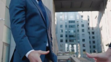 İş adamlarının el sıkışması. İki işadamı modern iş binası arka planında el sıkışıyor..