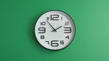 Yeşil arka planda asılı tek beyaz ofis saati